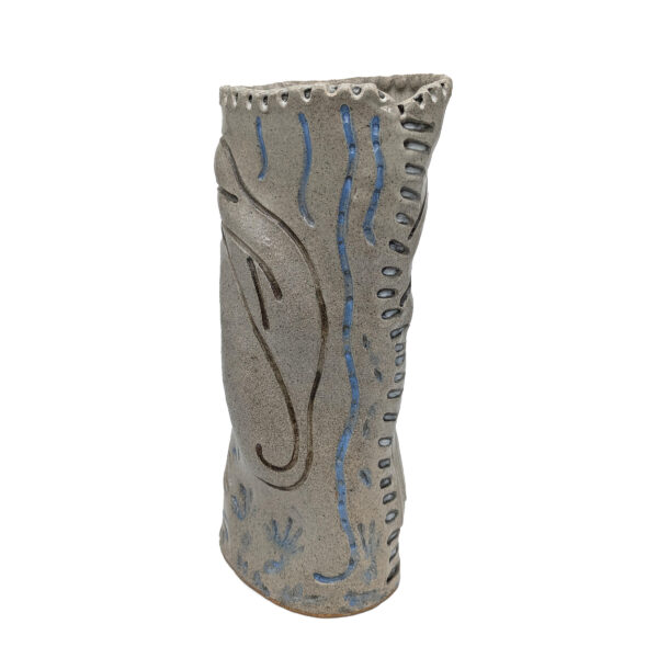 Cylindrical gray sculpture. There are abstract etchings of lines in black and blue, curves and hashes all around the sculpture.