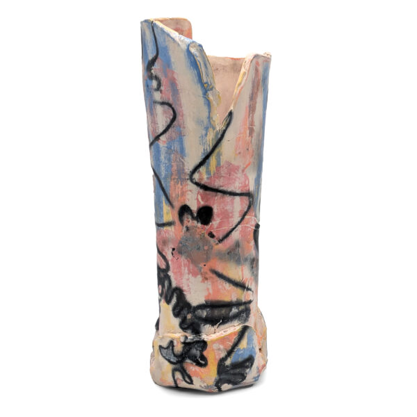 Cylindrical ceramic sculpture. The top of the sculpture has jagged, broken edges. The sculpture is painted with streaks of blue, pink and orange. There are black lines, dots and scribbles all over the sculpture.