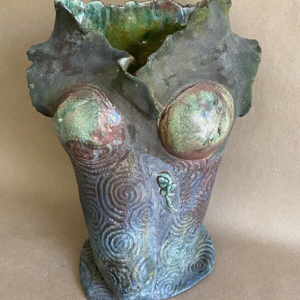Ceramic sculpture of a female torso in hues of green. The sculpture is etched with swirled patterns.