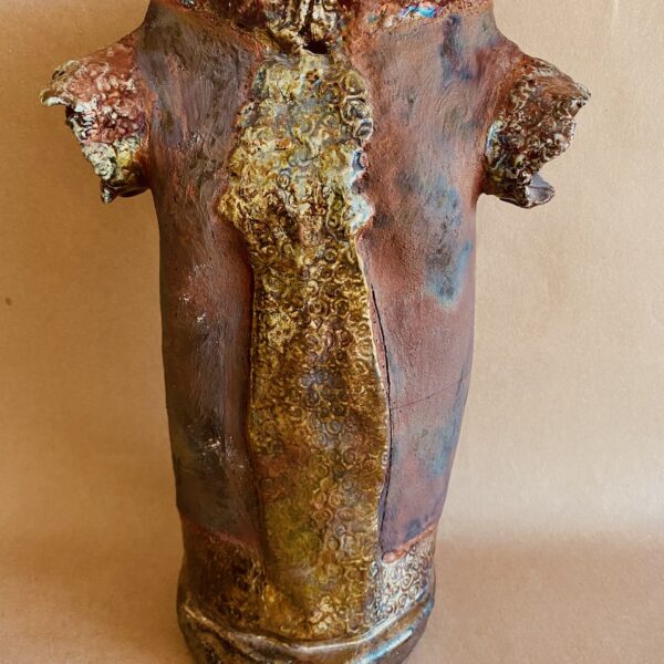 Abstract ceramic sculpture of a torso. The sculpture is brown with gold accents. Two short stumps protrude from the shoulders.