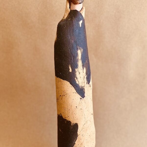 Tall abstract female ceramic sculpture in mixed black and white colors. The figure appears to have a slight smile.