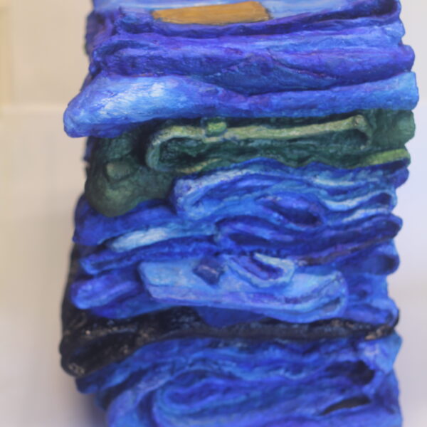 Photograph showing 3d art piece. The art is a stack of blue jeans.