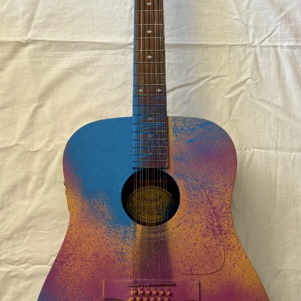 Image shows a 3D guitar on a white backdrop. The guitar is painted with shades of brown, yellow, pink and blue