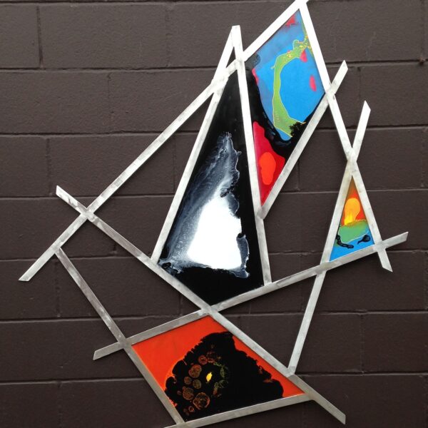 Photograph shows wall art. The art is made of long steel rods arranged in a random pattern. Colorful abstract images sit in between the rods.