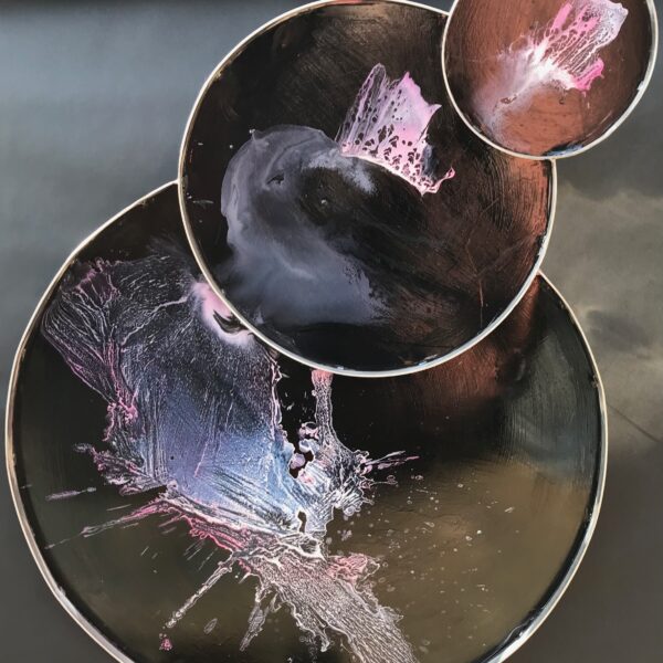 Photograph showing sculpture with three plates decorated with purple abstract paint.