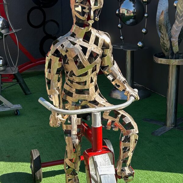 Image shows bronze sculpture of boy on a red bike